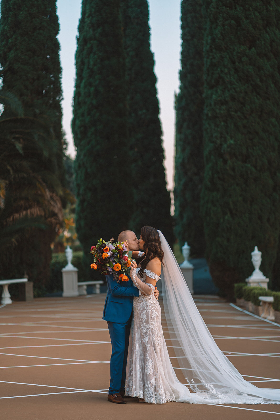 bride and groom kiss with jewel tone bridal bouquet