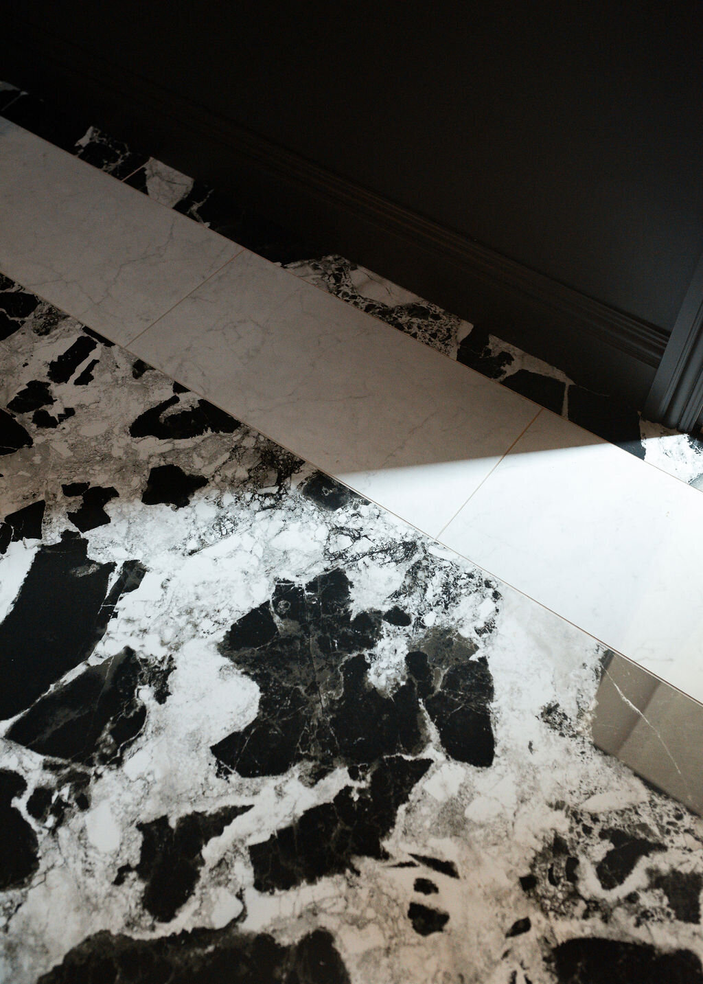 A close-up view of the marble flooring in a dark, modern bathroom.