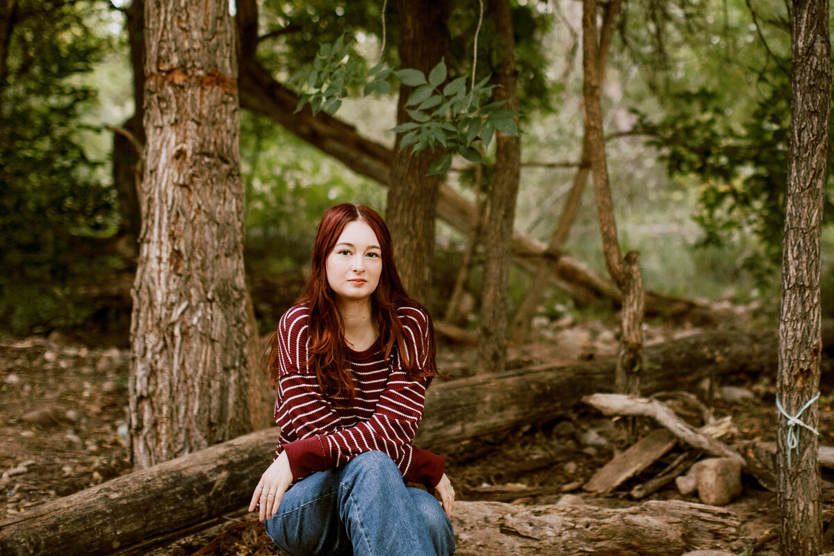 Erie High School Colorado Senior portrait of teen sitting on log in woods