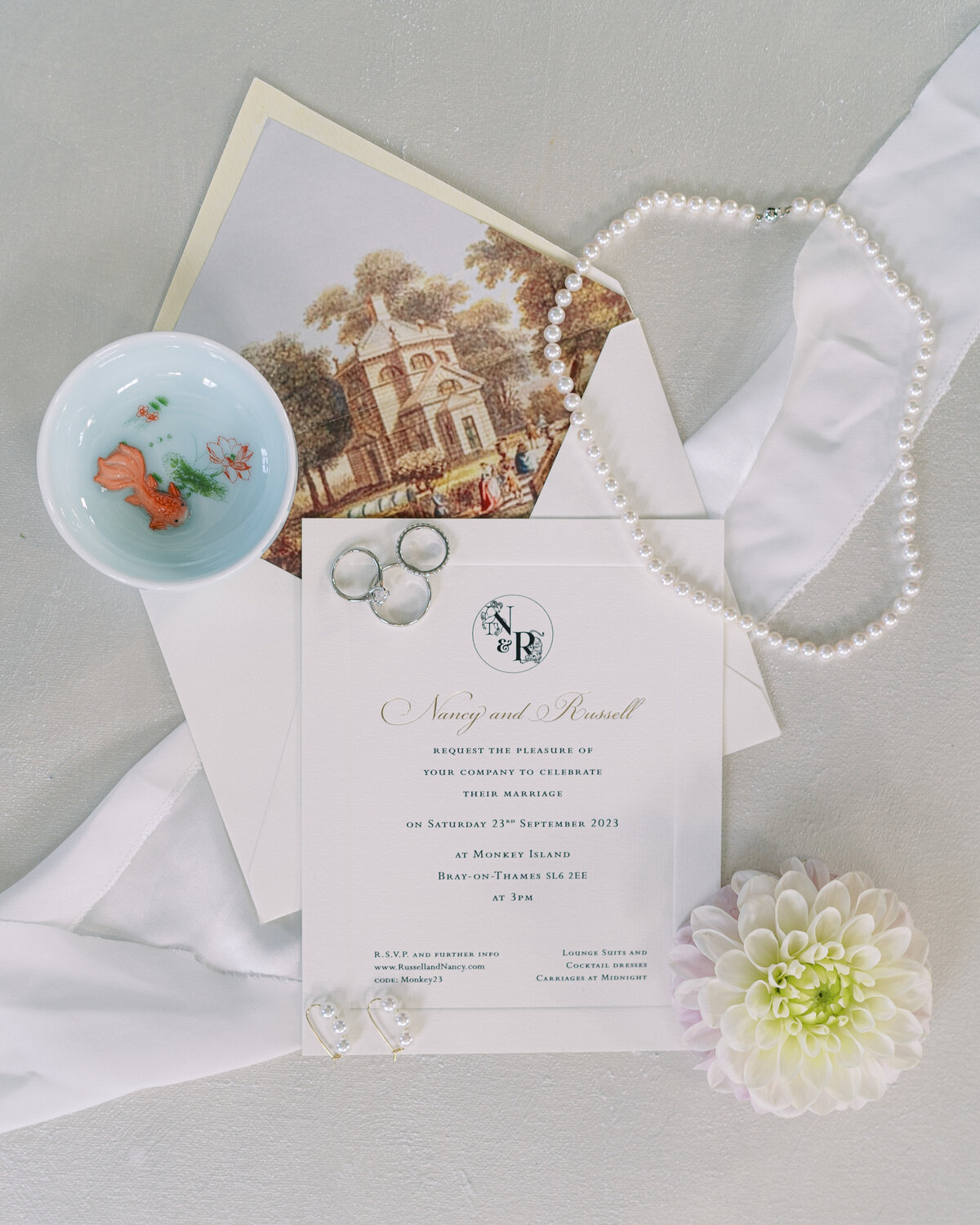 Wedding flatlay with wedding stationery, wedding rings, jewelry and florals