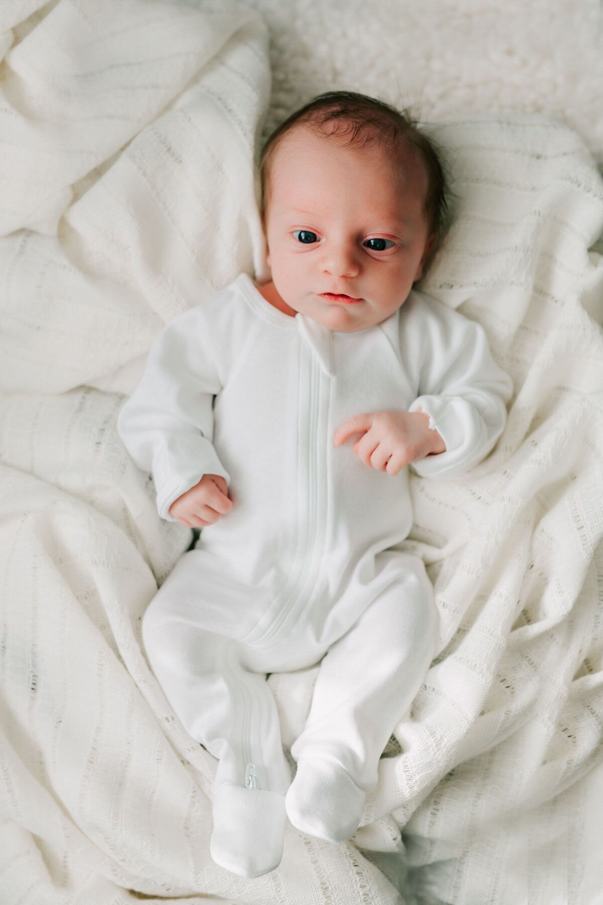 Newborn baby in a white onesie