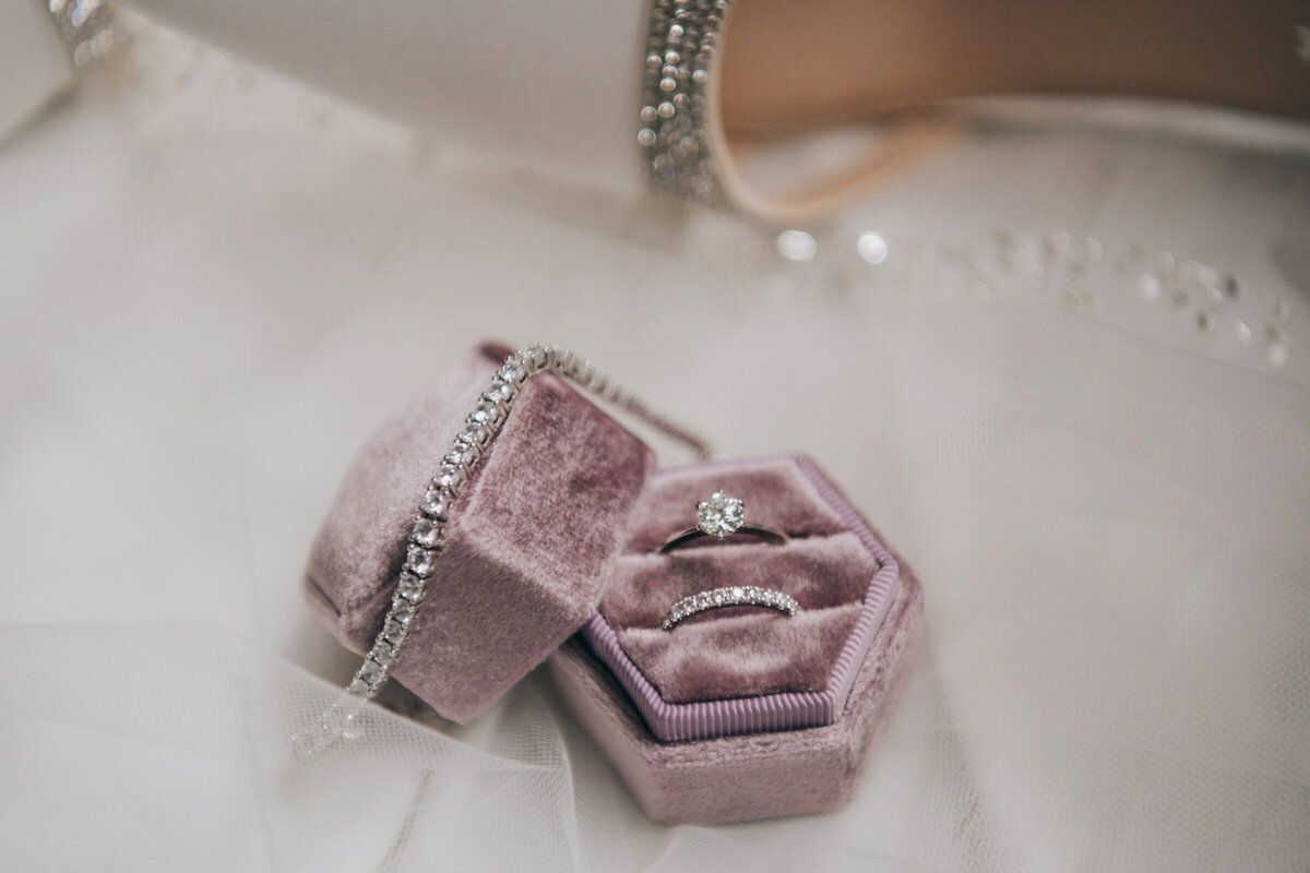A wedding ring and diamond bracelet in a purple velvet ring box