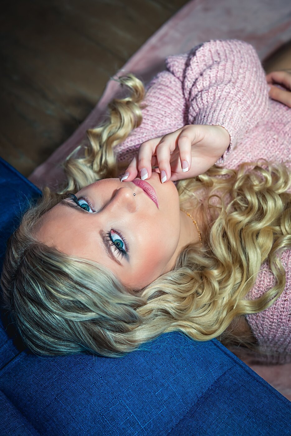 A woman in a pink sweater poses during her boudoir shoot.