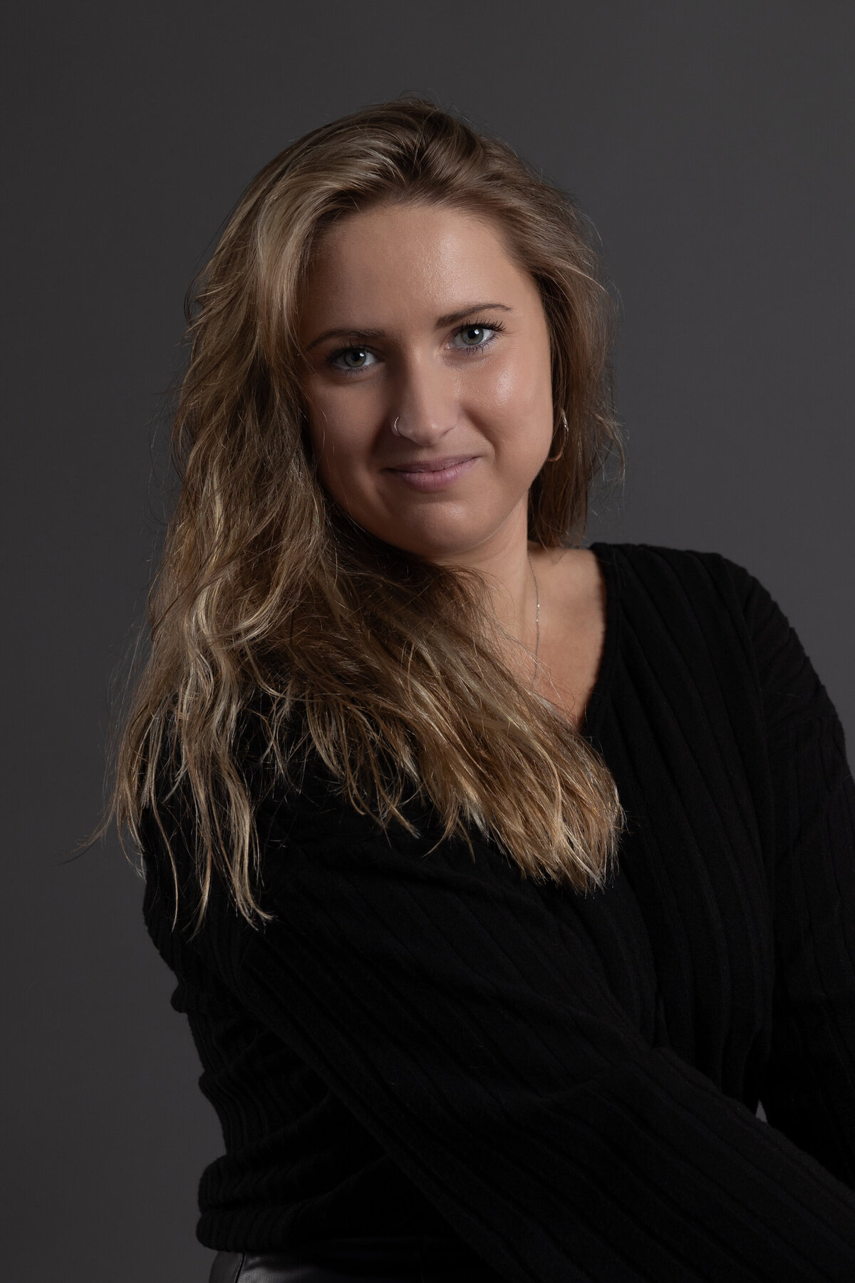 Jeune femme vêtue de noir sur fond gris Photographie de studio Montréal