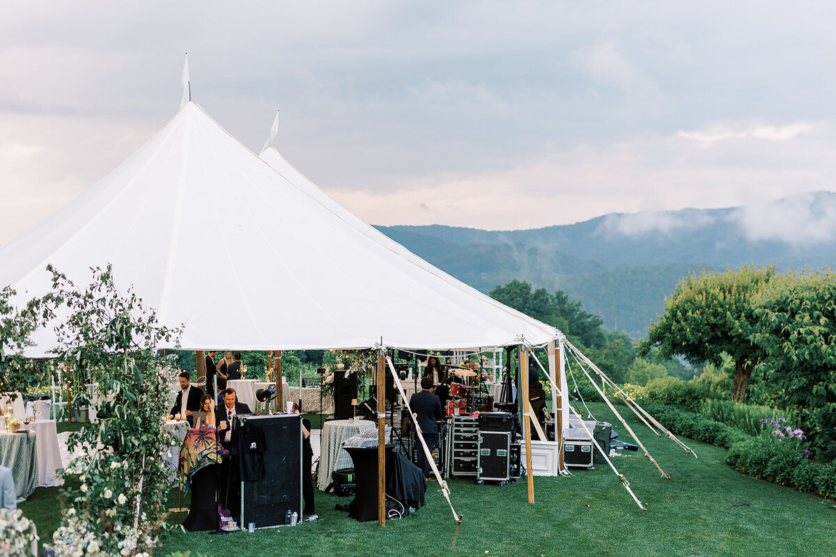 Guests mingling during cocktail hour outside a sailcloth tent with sweeping mountain and lake views at Trillium Links & Lake Club.