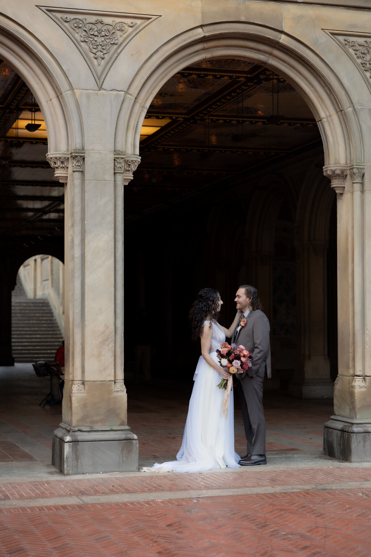 The couple sharing a tender moment beneath Central Park’s beautiful stone arches.