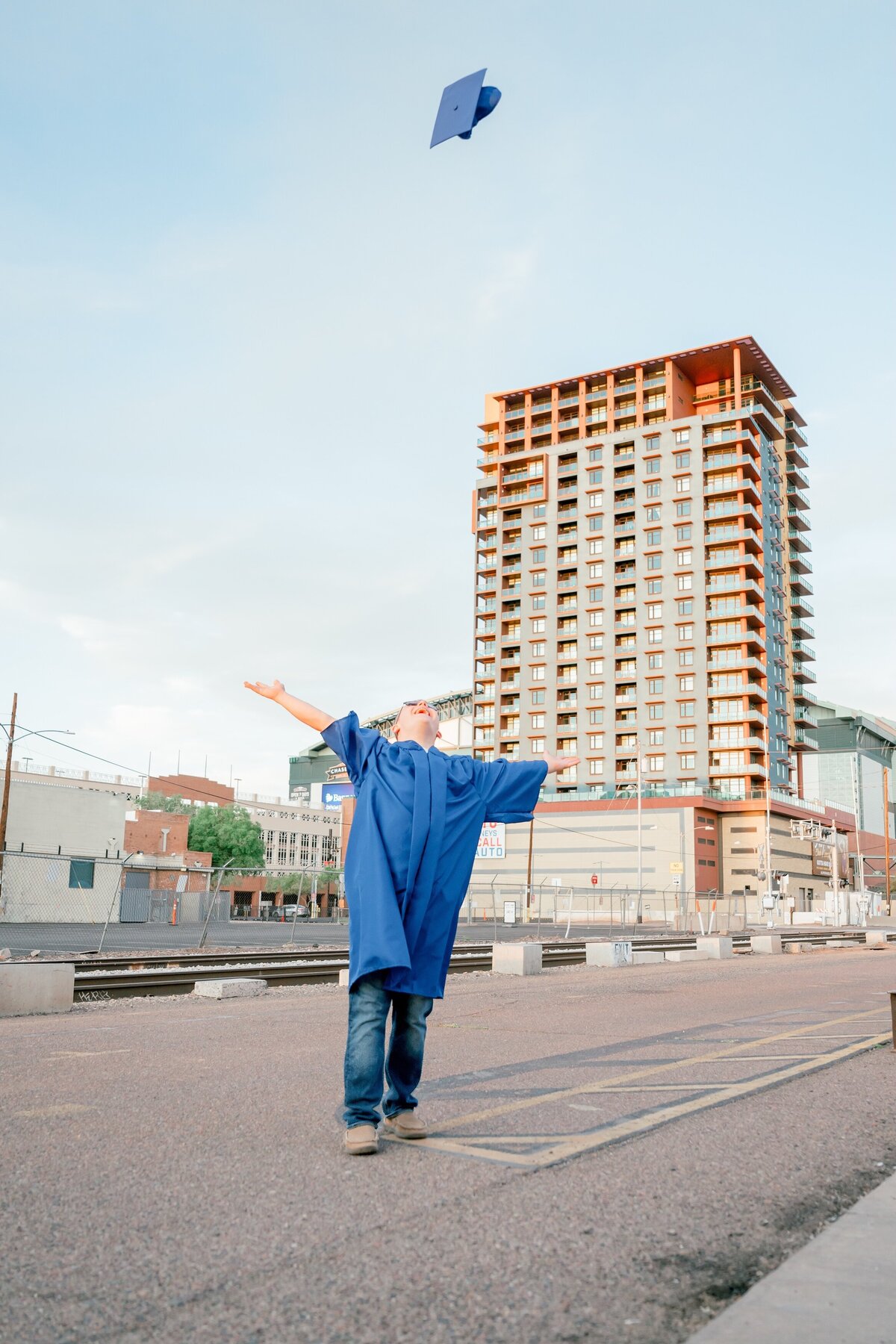 senior boy throwing cap into the air in downtown phoenix 