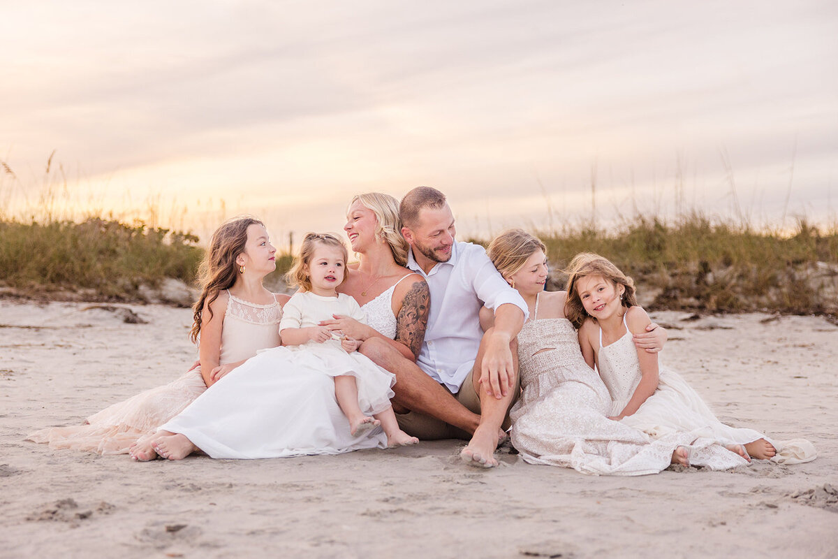 Golden hour beach portrait of a young girl laughing with her family
