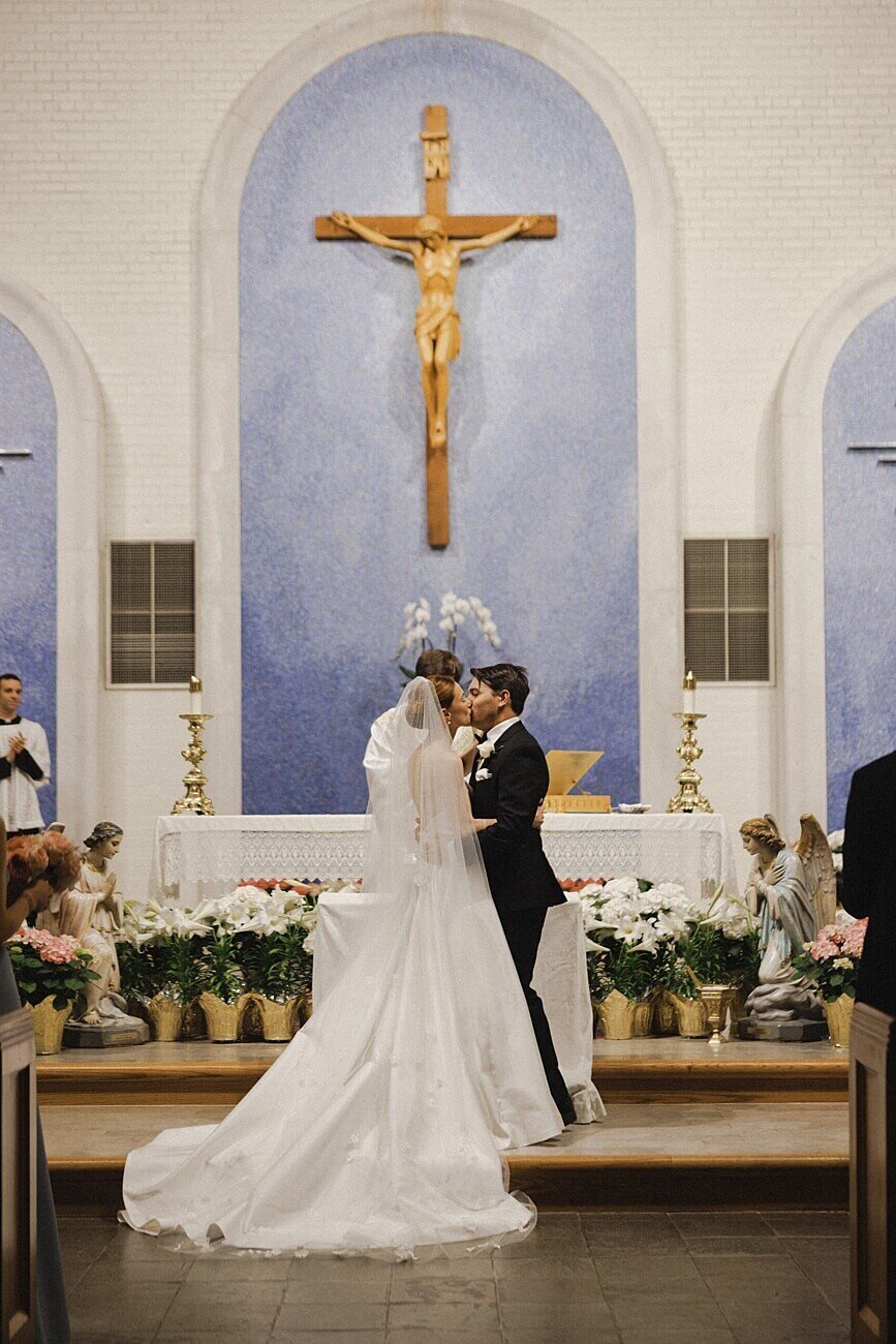bride and groom first kiss in church at the alter