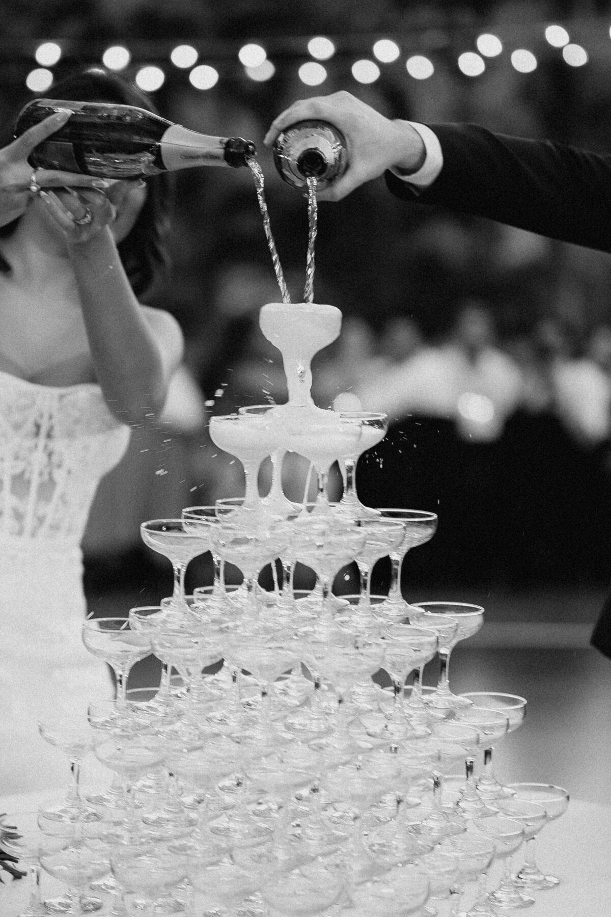Bride and groom pouring champagne tower in front of their guests