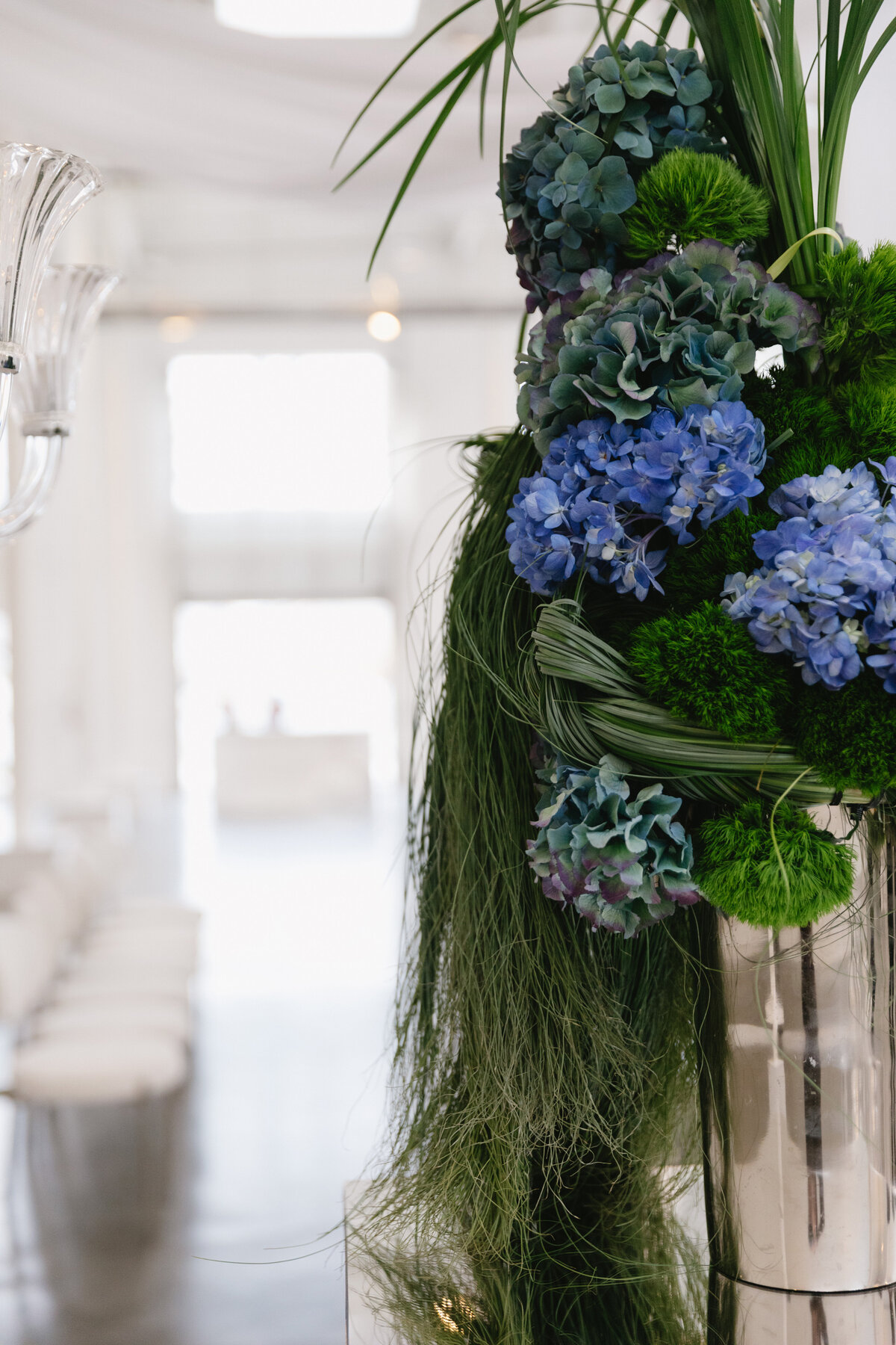 Fashion-forward wedding portrait of bride and groom inside a minimalist white studio with soft natural light.