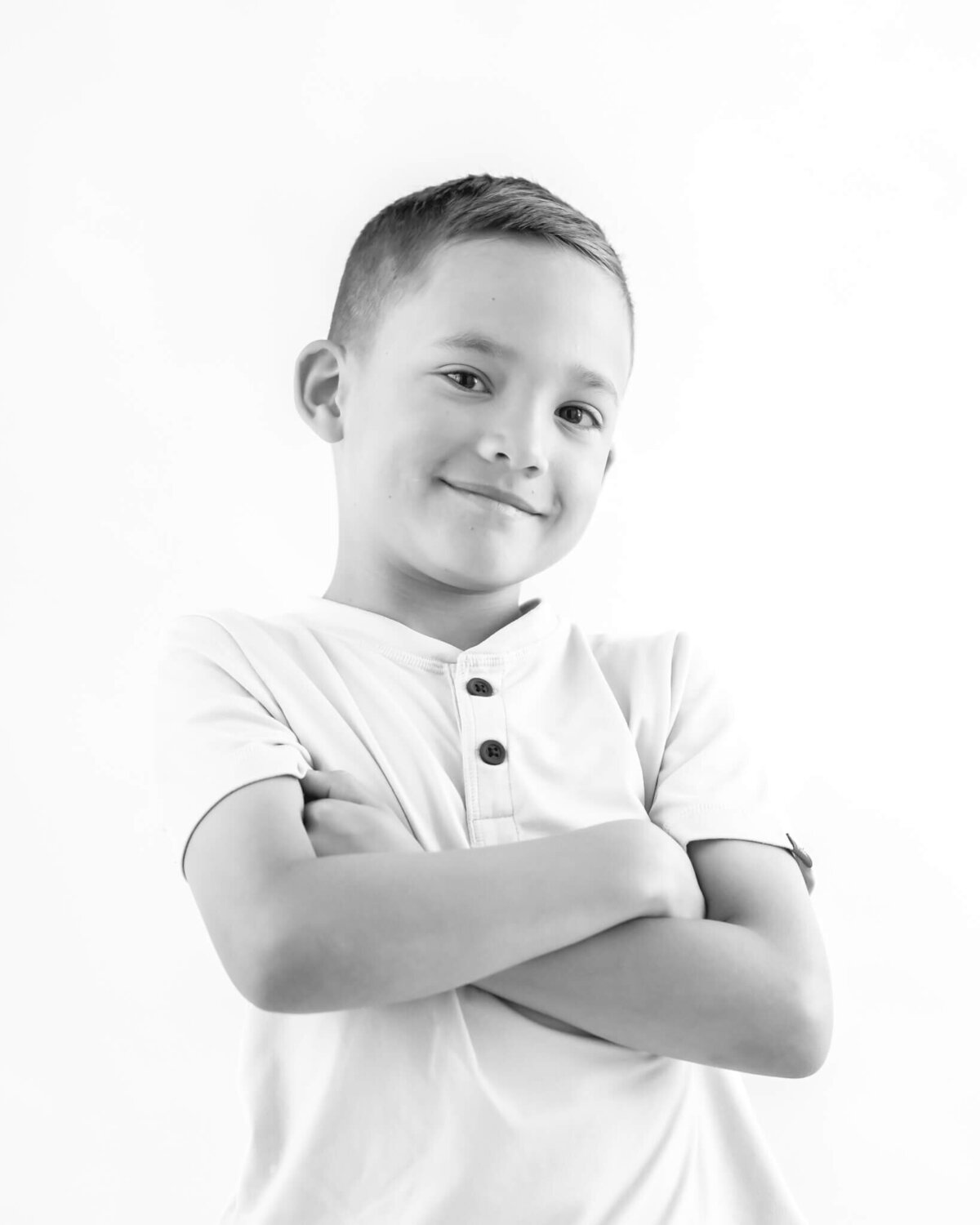 black and white portait of little boy with arms crossed and a smirk on face