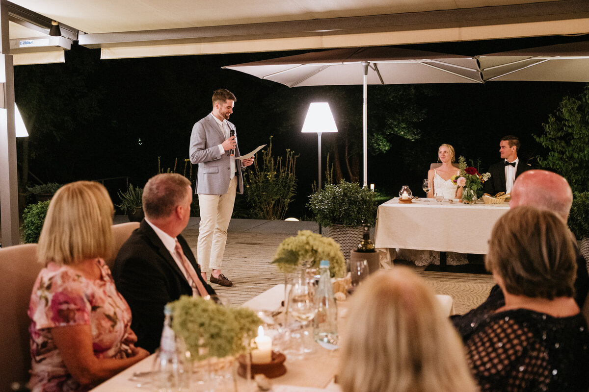 Wedding guest giving speech during outdoor dinner