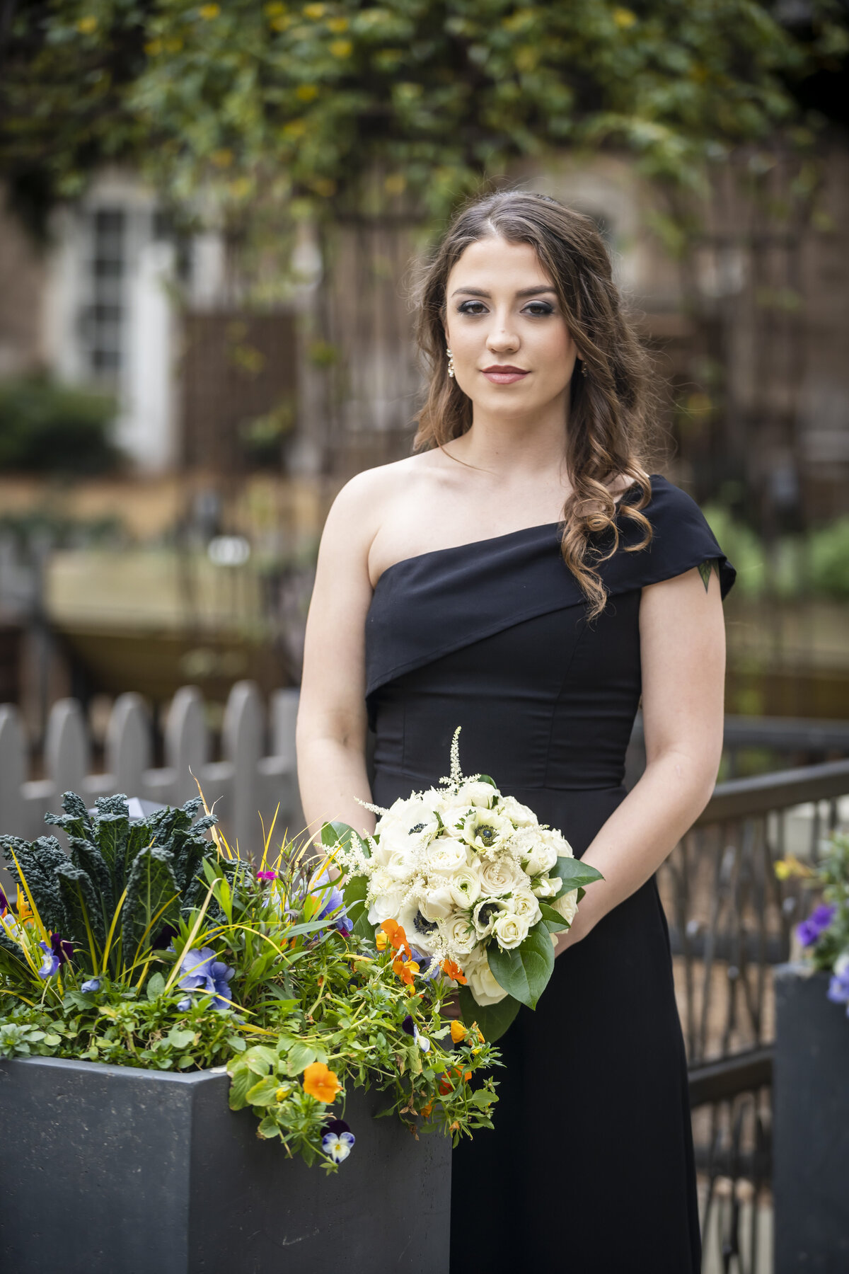 Bridesmaid in black dress holding bouquet.
