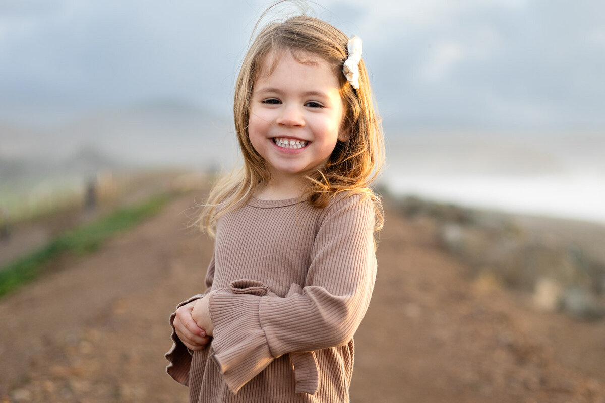 Young girl wit white hair bow smiling for Bay Area school photography lifestyle portrait – Ellobelle Photography