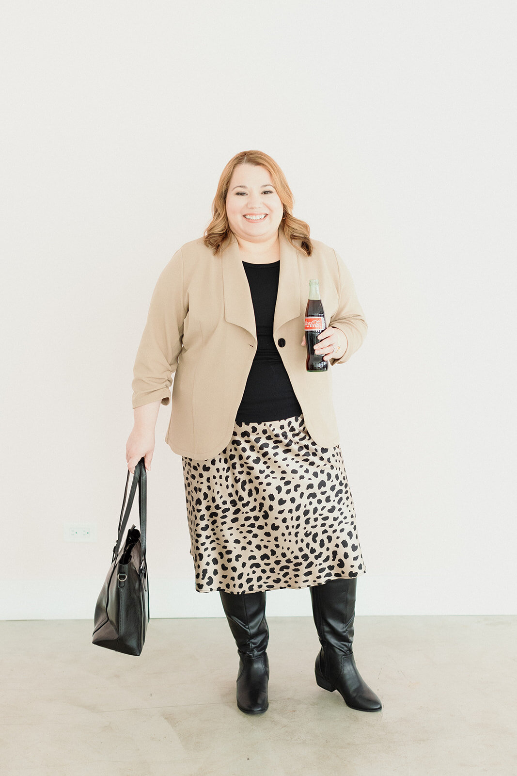 professional woman smiling and holding her bag and a cola drink