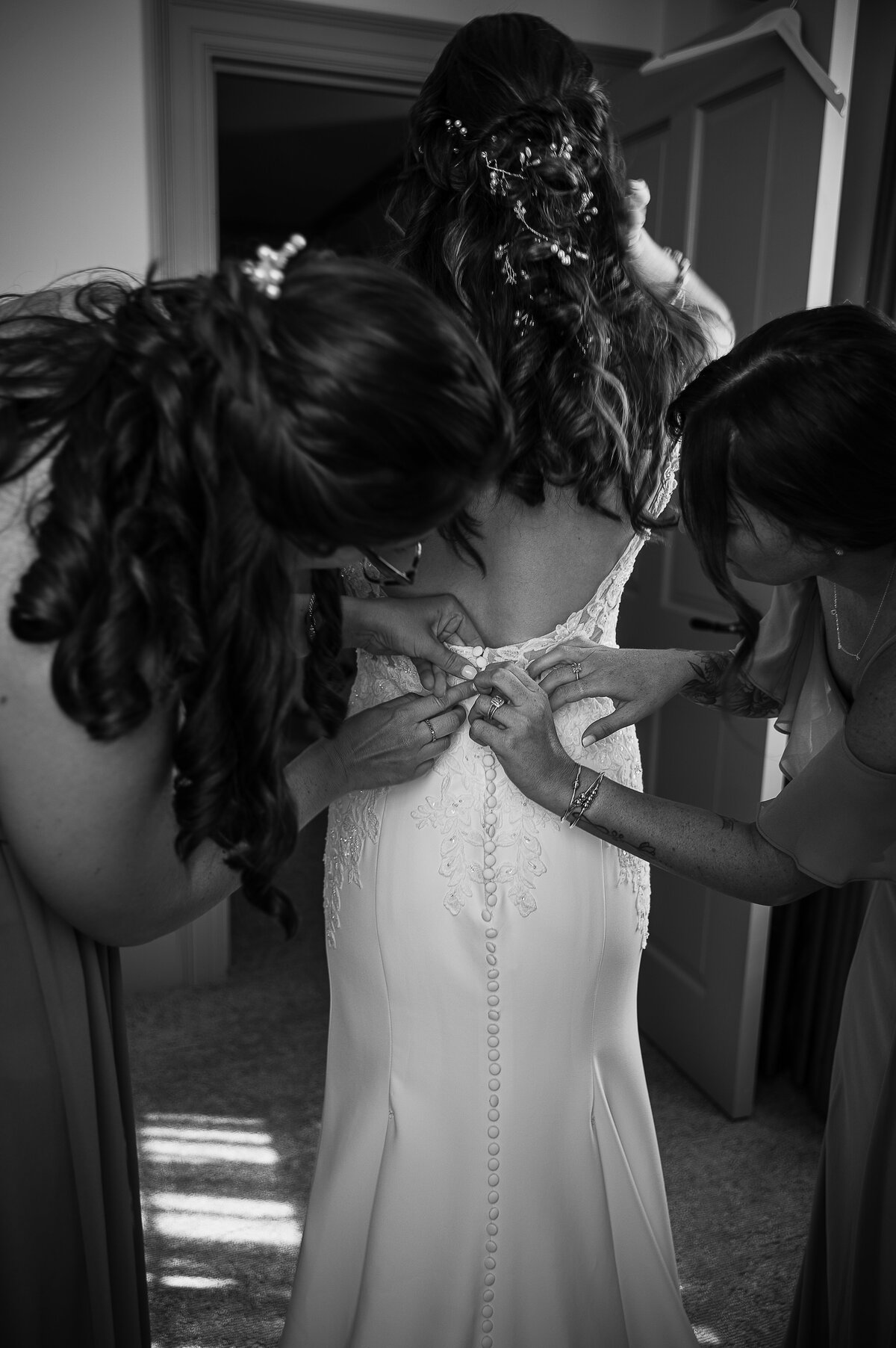 bridesmaids zipping the bride into her wedding dress