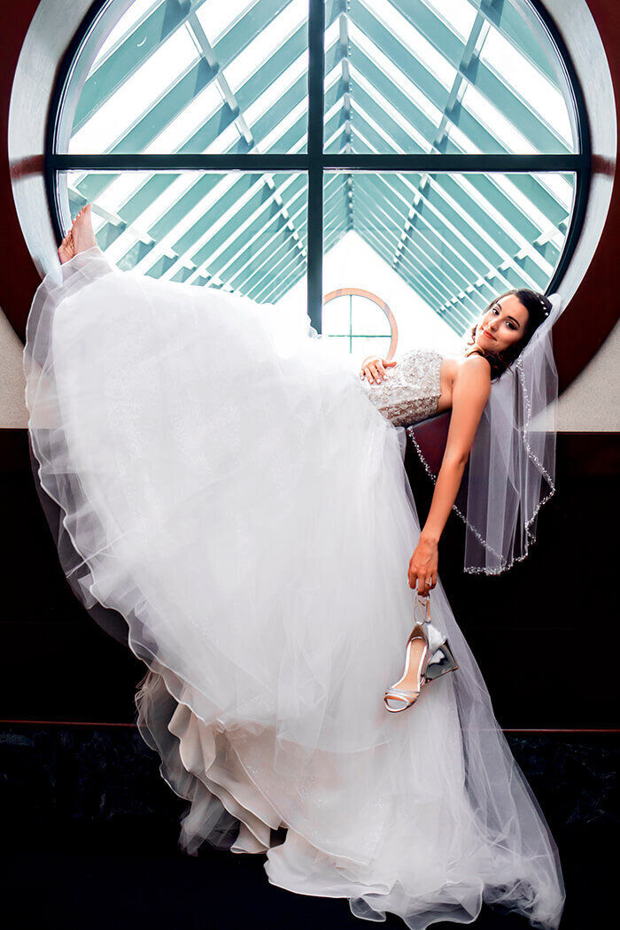 bride-lays-in-window-holding-shoes