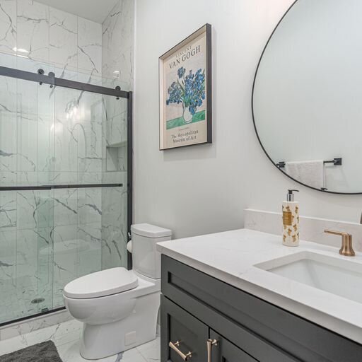 A bathroom with marble counter tops and a glass shower door
