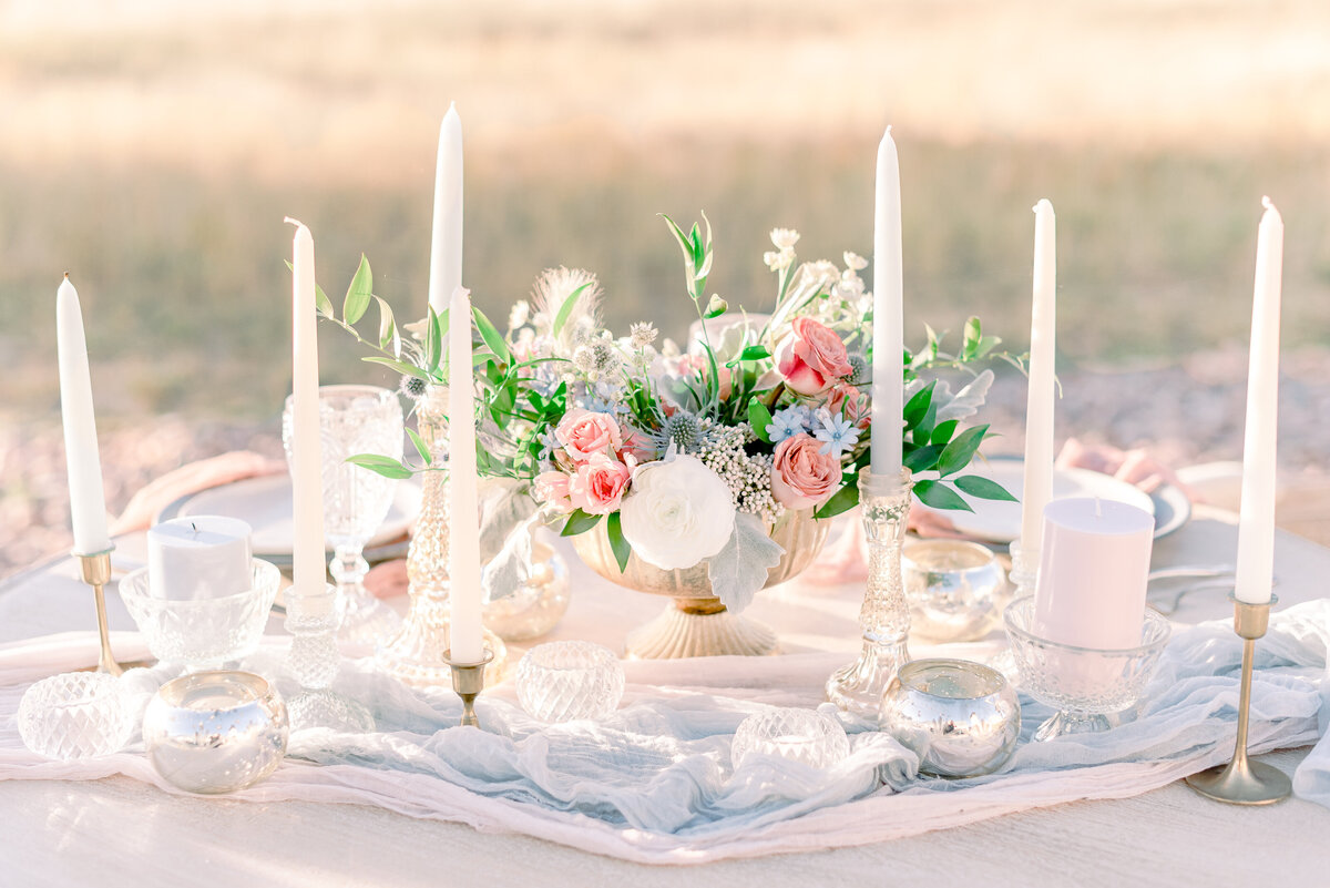 a romantic fine art wedding photograph of a beautiful table scape using the bridal bouquet and chandlerie candles at the flying horse ranch venue