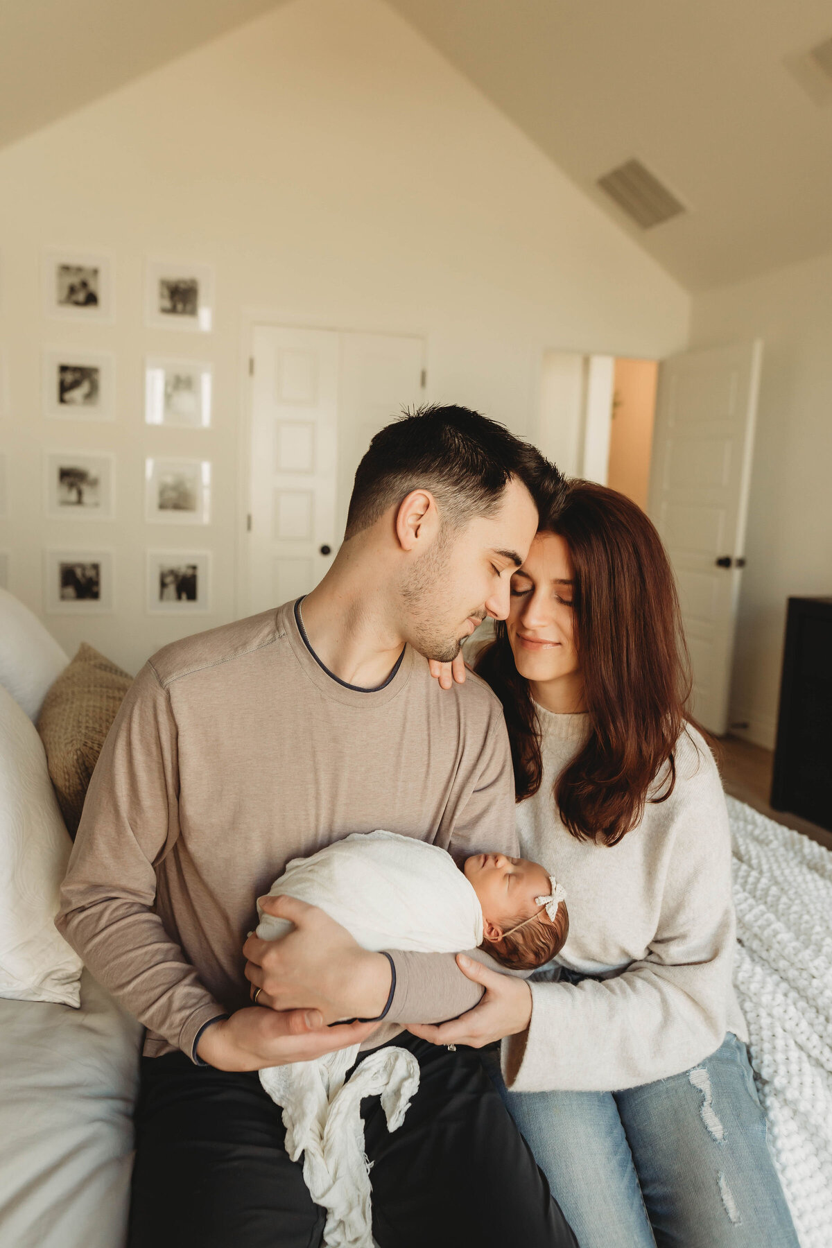 new parents snuggle up while holding their newborn baby