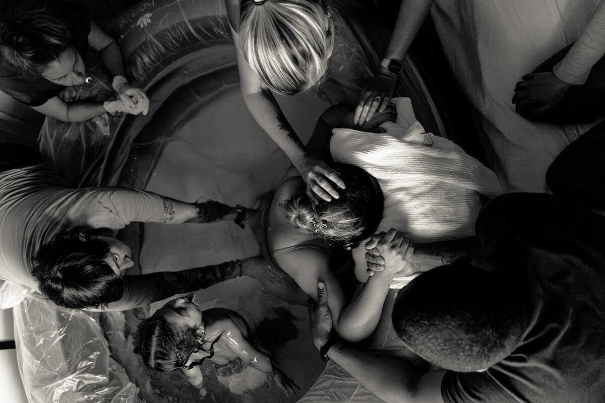 Mother is supported in home birth by midwife team, birth doula, husband, mother, and eldest child