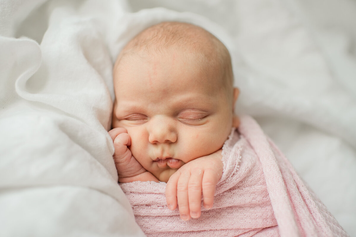 sleepy and squishy newborn in a soft pink swaddle
