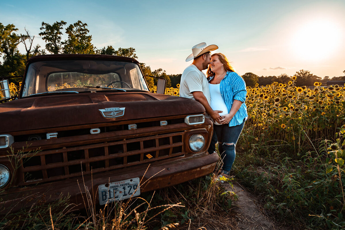 Couple in a field of sunflowers by an old truck