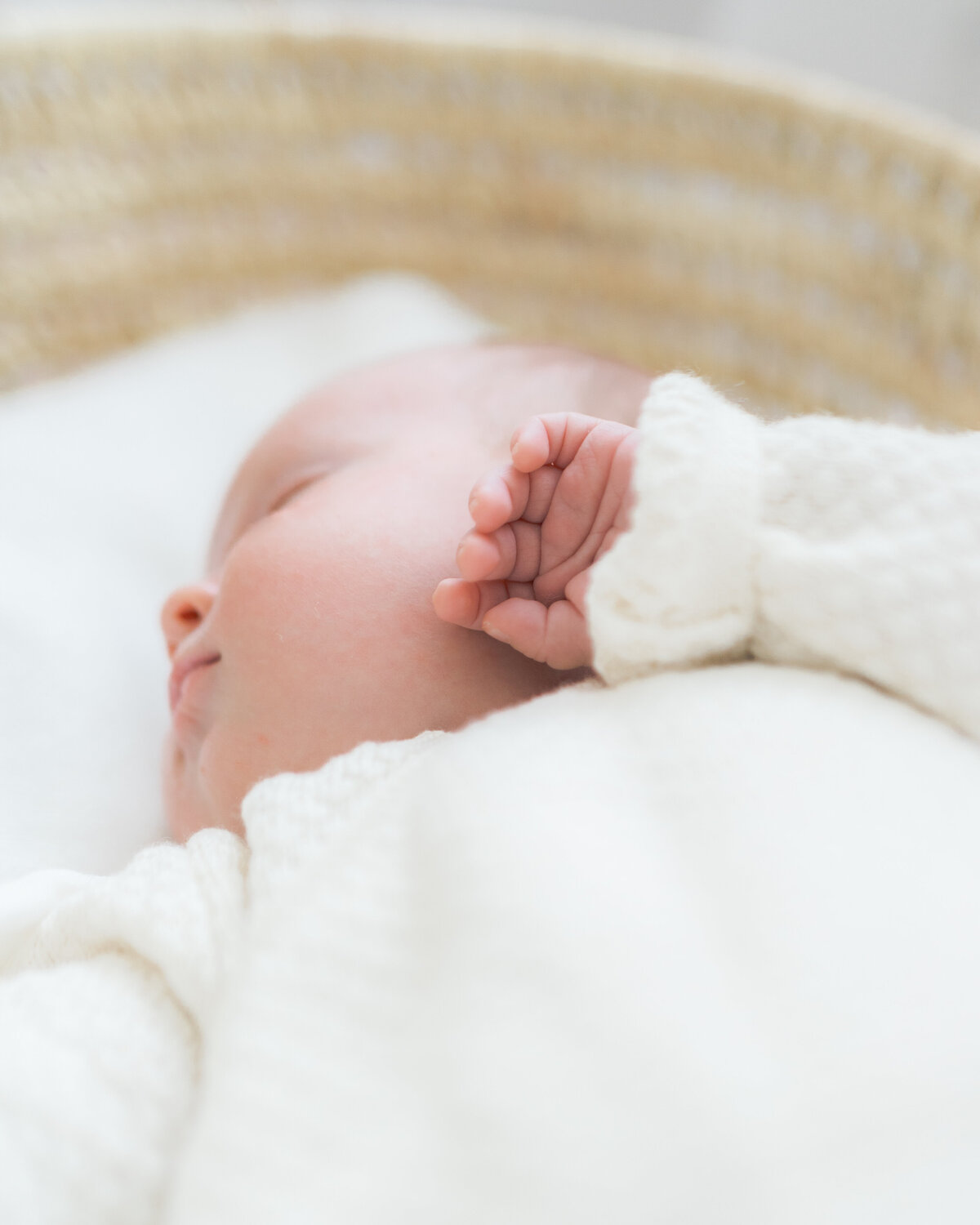 Detail photo of newborn baby's little hand resting on her cheek by Oklahoma City newborn photographer Courtney Cronin