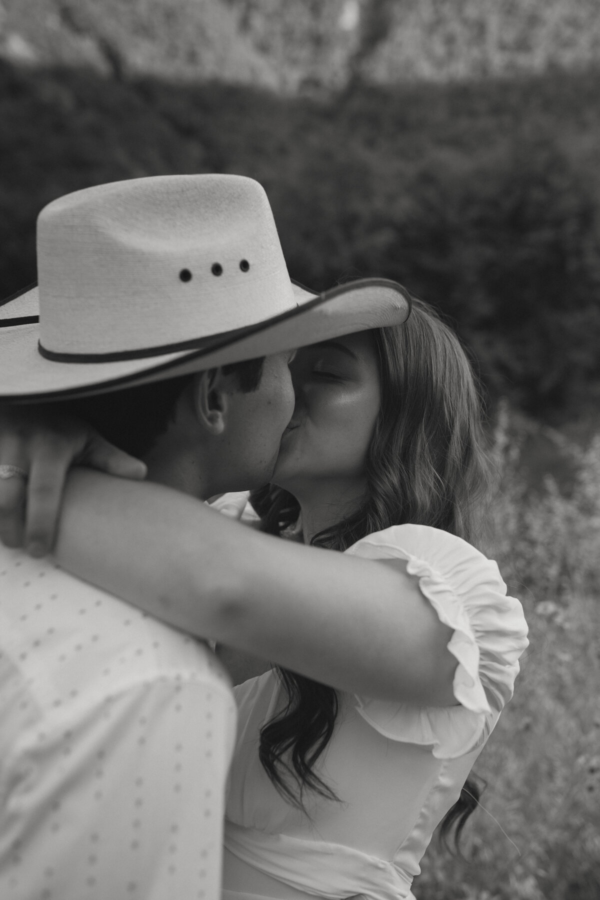 black and white photo of couple kissing  in a field