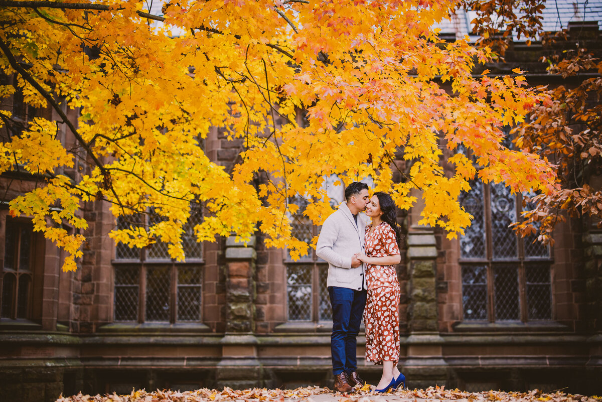 Engagement couple share a moment near a bright orange tree in the fall at princeton university in nj
