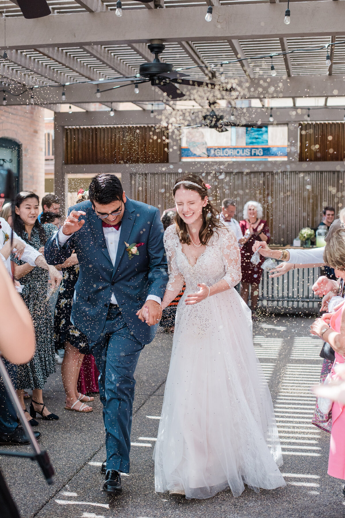 wedding exit with rice being thrown at the bride and groom as they rung from their reception while holding hands captured by denver wedding photographer