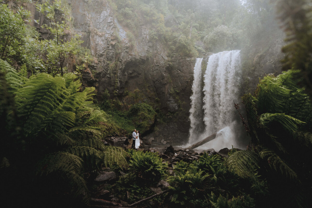 Bride and Groom standing in front of a water fall