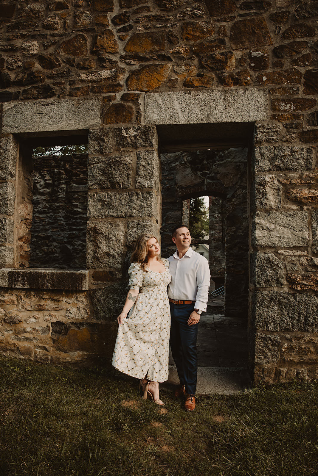 A couple standing close and leaning against an old building 