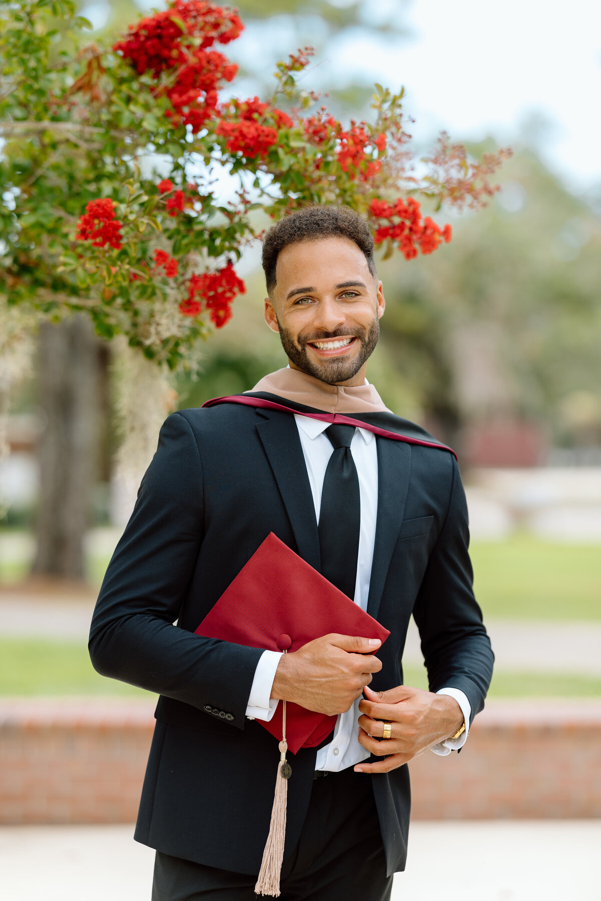 Florida State University law school graduate posing with his cap on campus near flowers