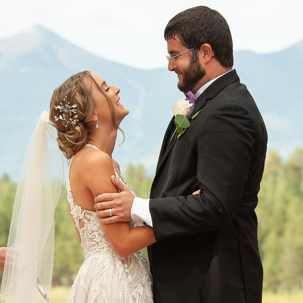 Groom embraces his bride as they smile on their wedding day