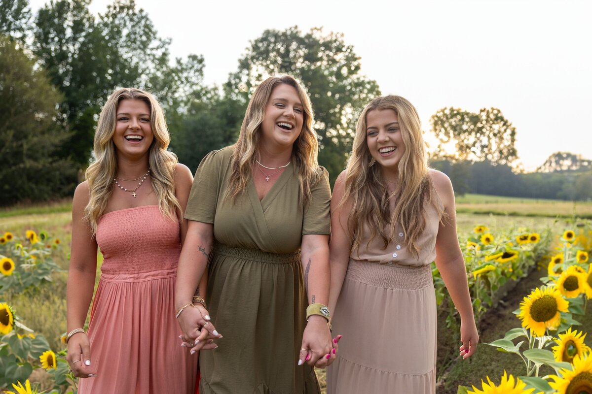three girls laughing in sunflower field