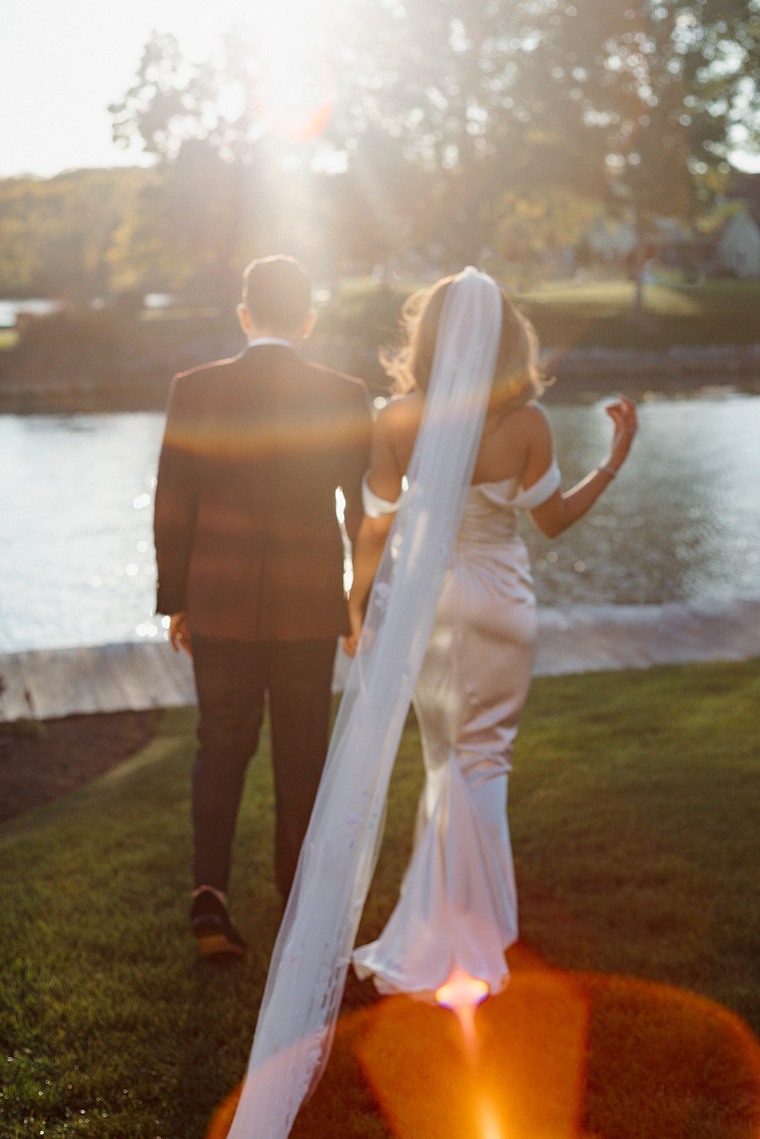 Bride and groom walk into the setting sun at The Lake House on Canandaigua