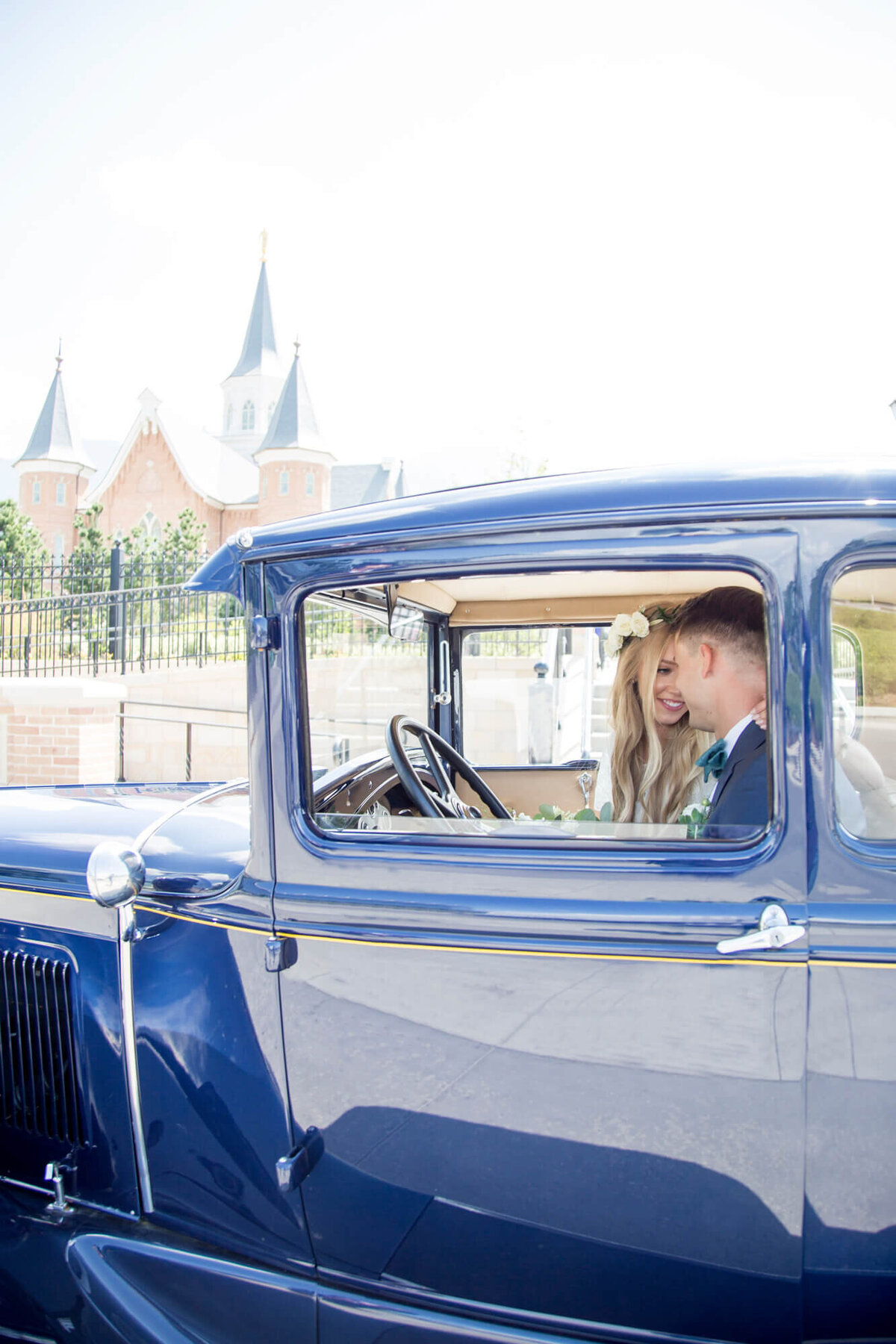 a couple in a vintage blue car on their bright and joyful wedding day