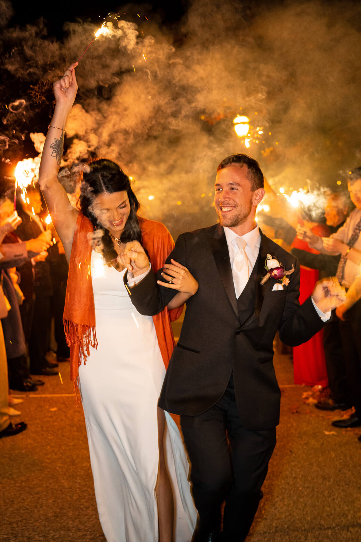 Bride and groom smile and laugh as they walk through their sparkler exit at the end of their wedding day at Phipps Conservatory and Botanical Gardens, Pittsburgh PA. Captured by Michael Fricke Photography, a Pittsburgh Wedding Photographer