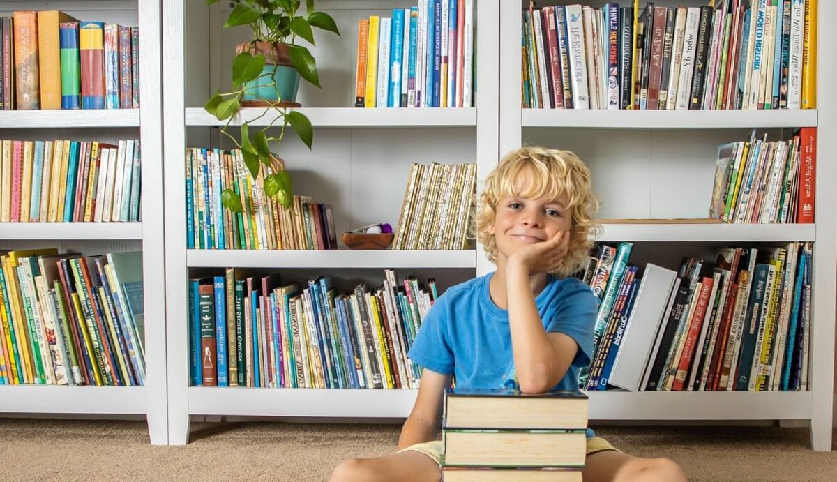 10 year old dyslexic boy with a stack of Keeper of the Lost Cities books he read