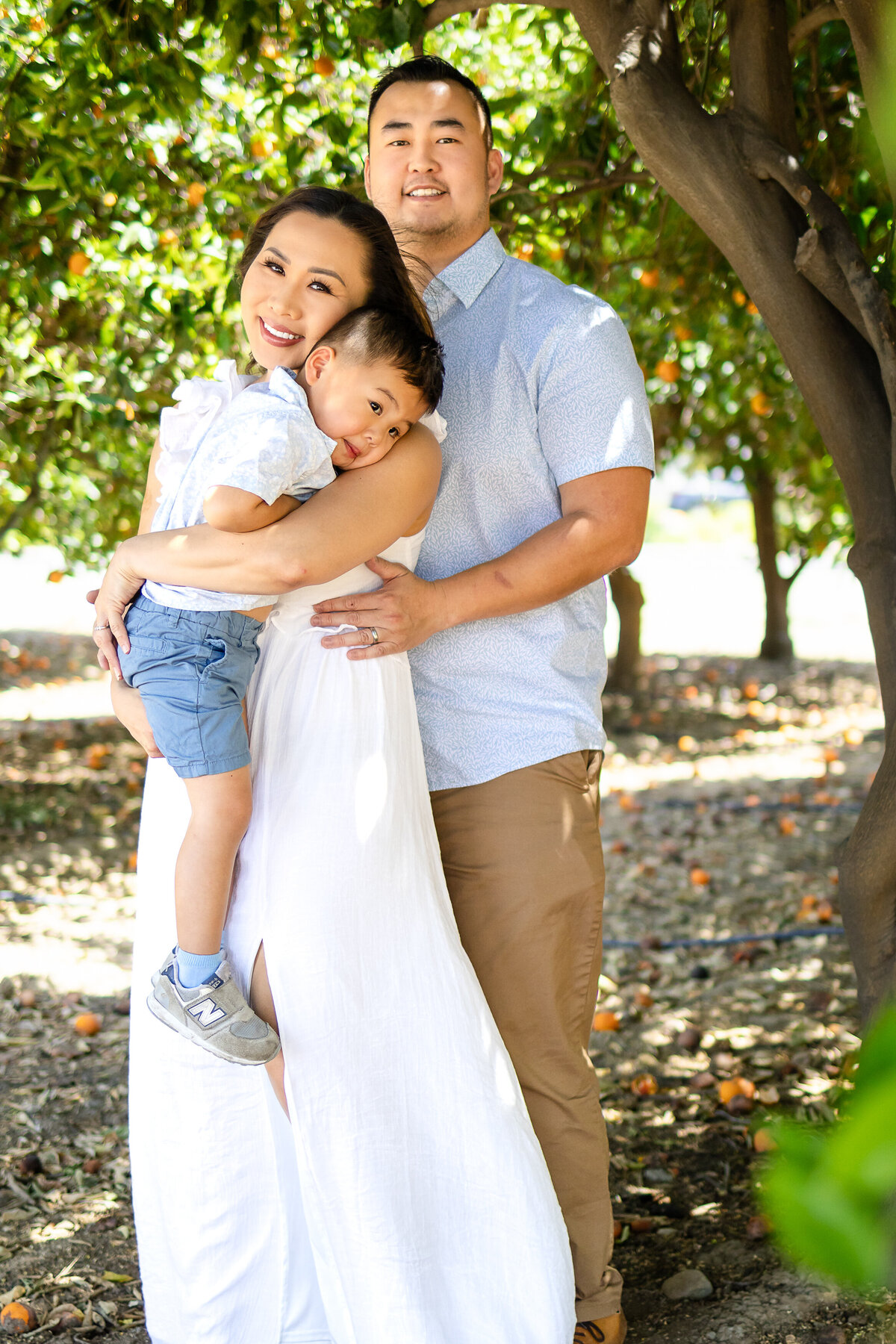 Mom and Dad sharing a warm hug with their toddler son during a playful outdoor session – lifestyle family photography by Ellobelle Photography, San Francisco Peninsula