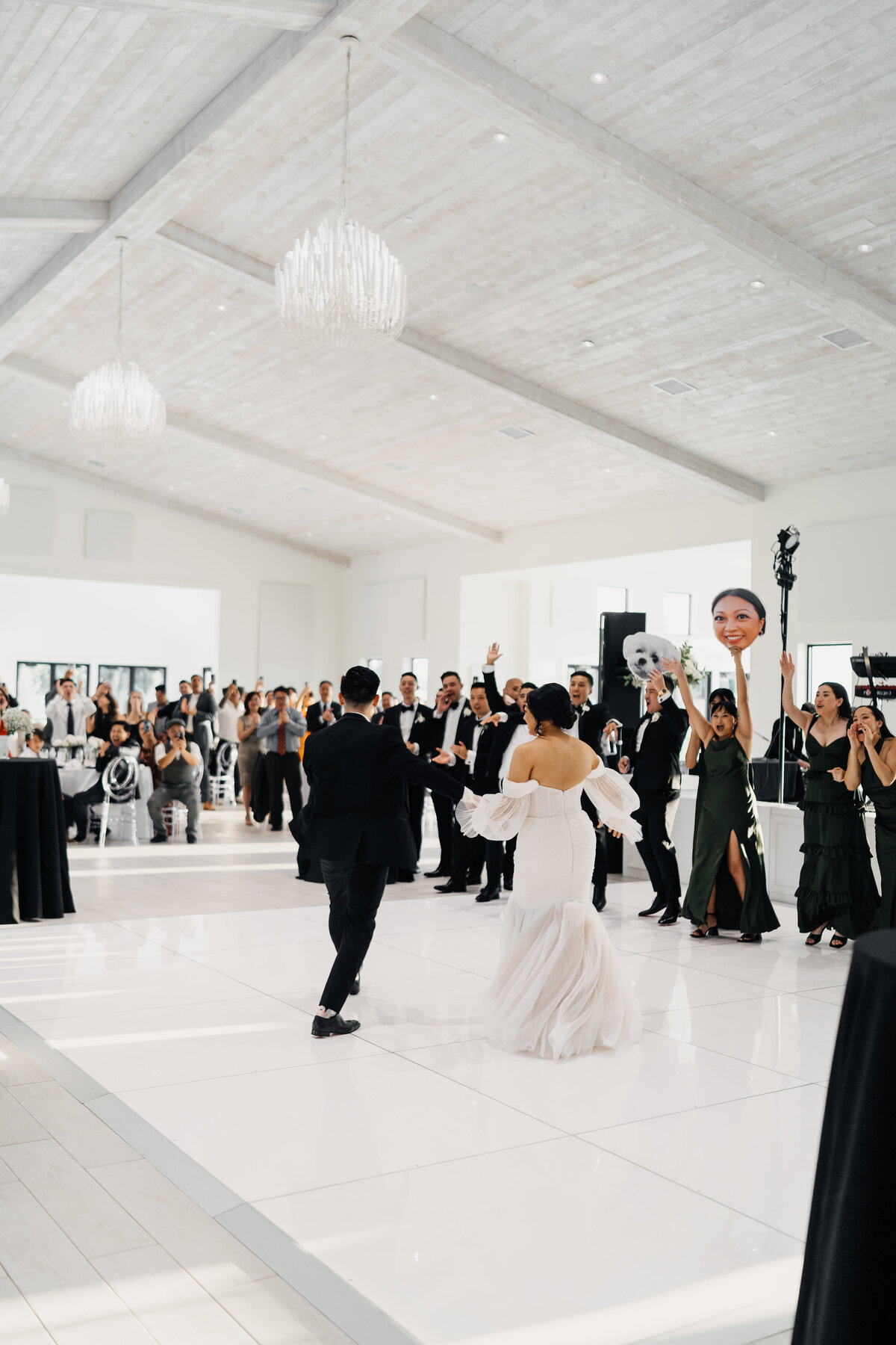 Couple popping champagne during their wedding reception, laughing with friends and family.