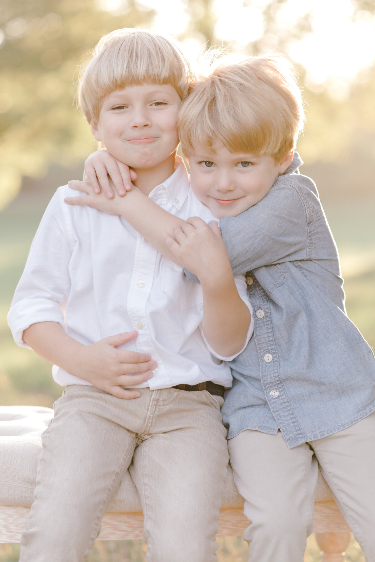 Two young brothers hugging each other and smiling at the camera with the Texas sun setting behind them