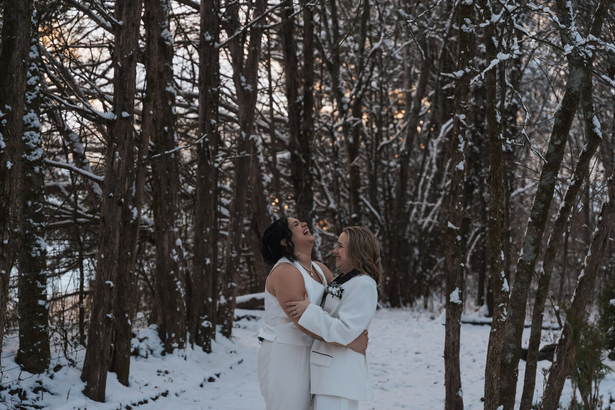 Women laugh together while embracing in the snow 