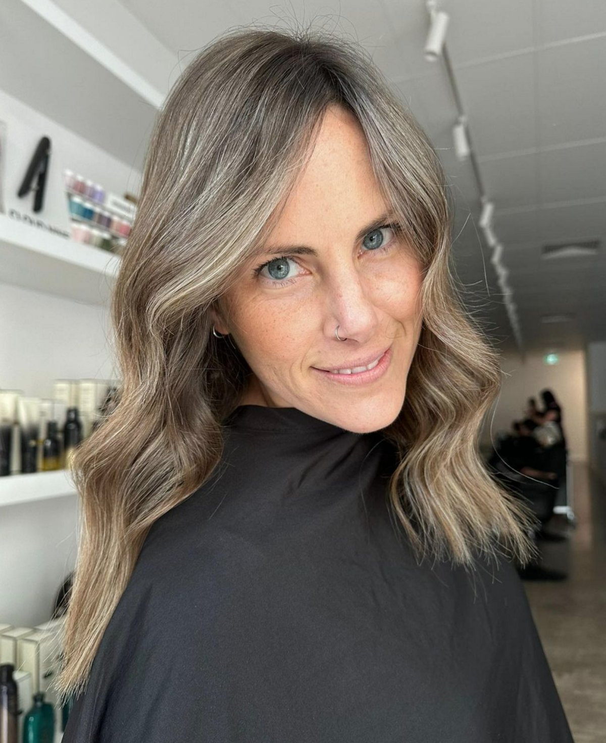 Woman I black hairdresser cape with freshly coloured hair - brunette with blonde foils