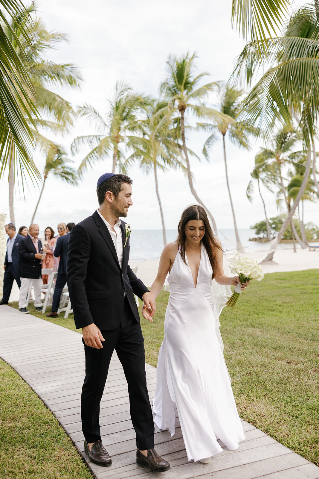 Minette and Evan joyfully walk hand in hand after their beachfront ceremony at Casitas at Cheeca. Islamorada wedding photography by Claudia Amalia.