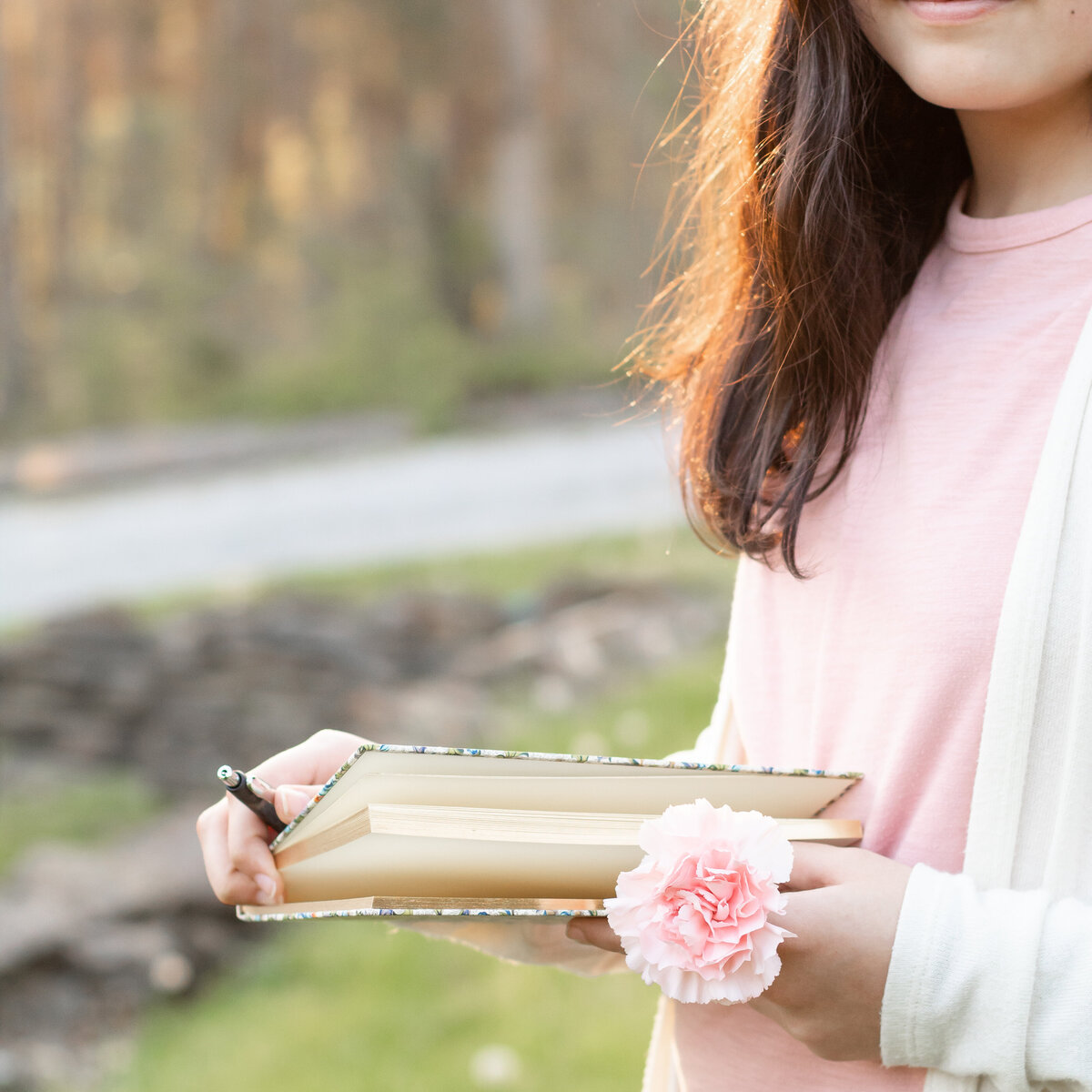 photo of young lady holding notebook and flower