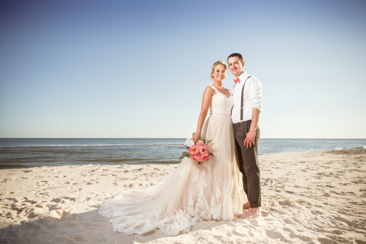 Newlyweds pose for a photo on the beach in Ft. Morgan, Alabama after their wedding ceremony.