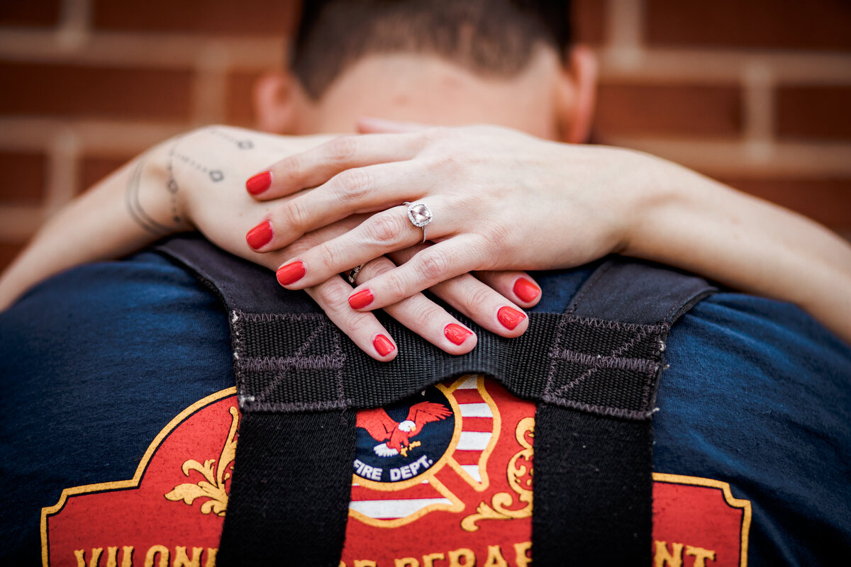 An engagement ring is shown on a firefighters back.